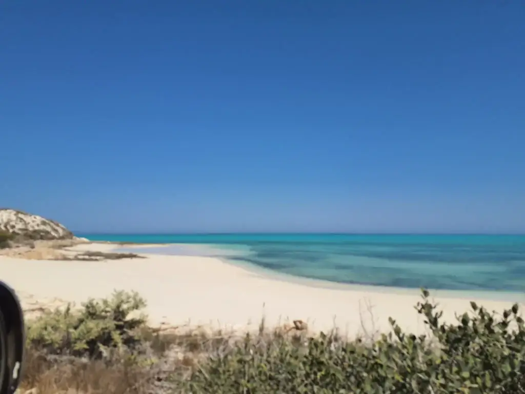 Plage de sable blanc et eau turquoise à Ambatomilo
